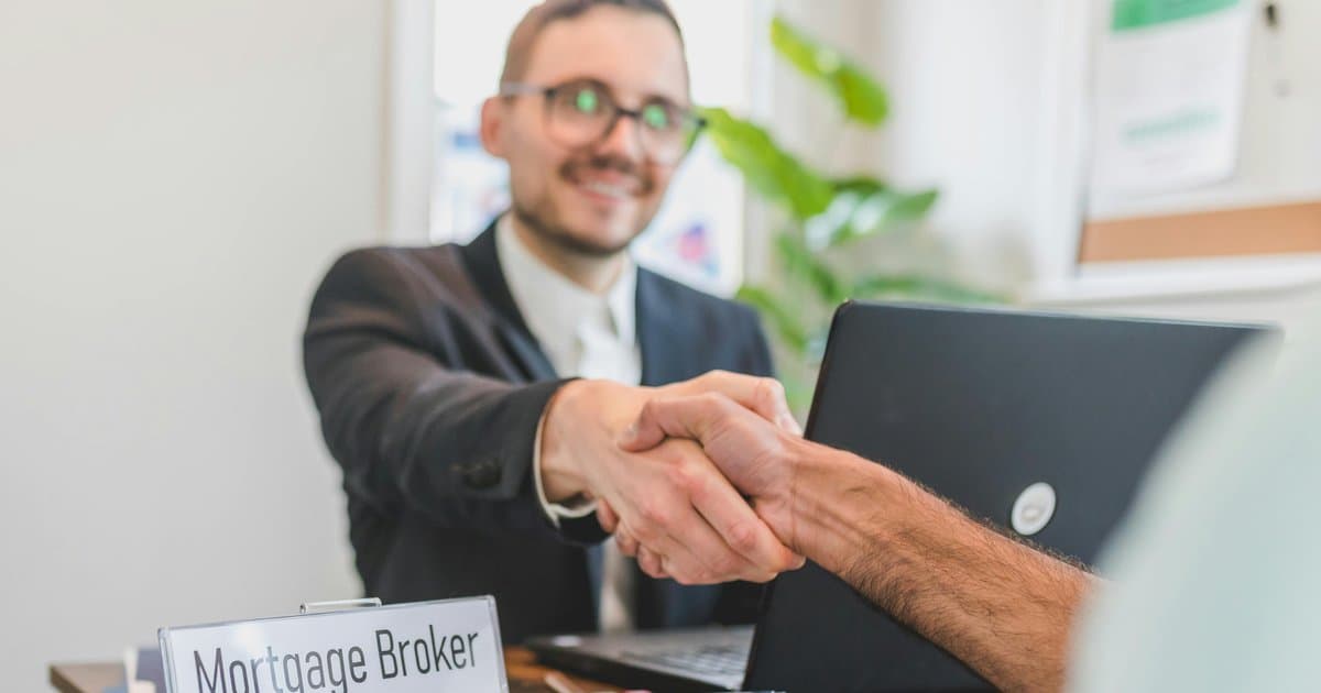 Mortgage broker shaking hands with client in office