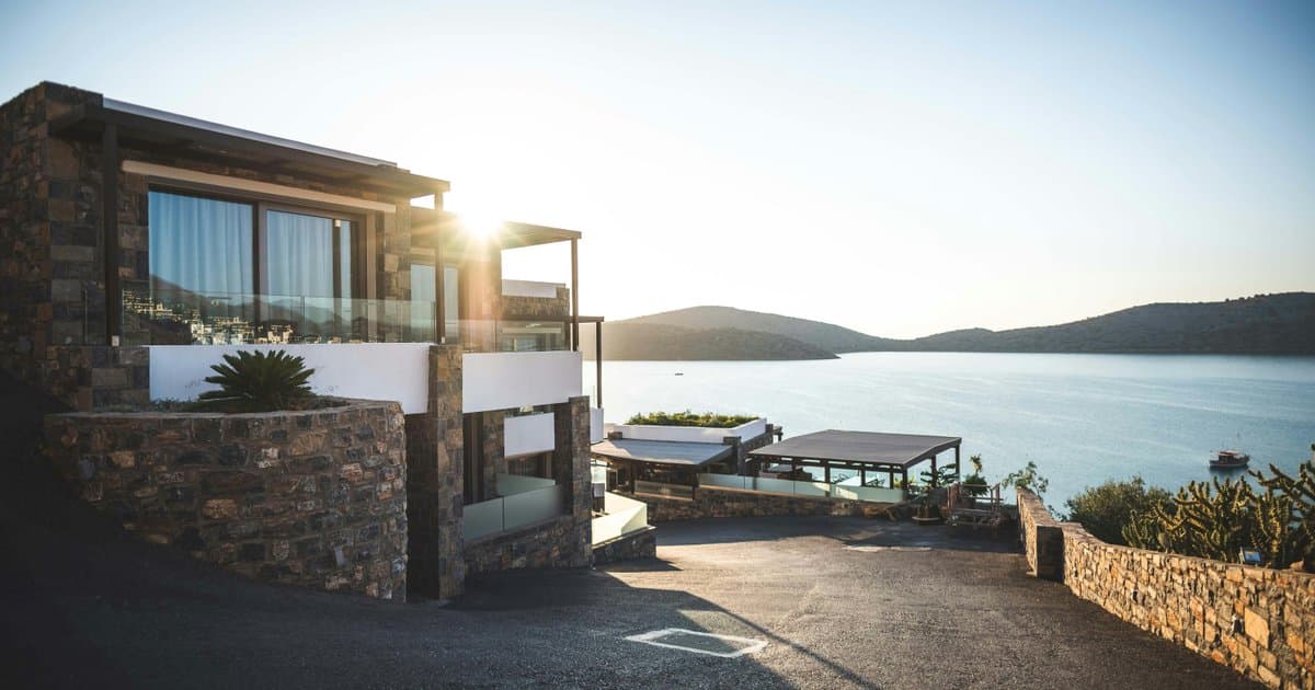 Luxury waterfront home with stone exterior at sunset
